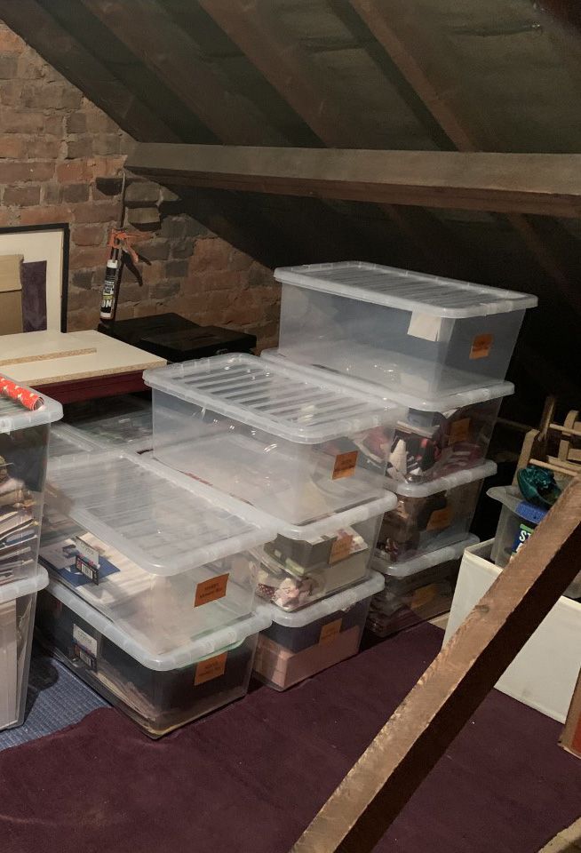 Clear storage boxes with orange labels stacked in a loft