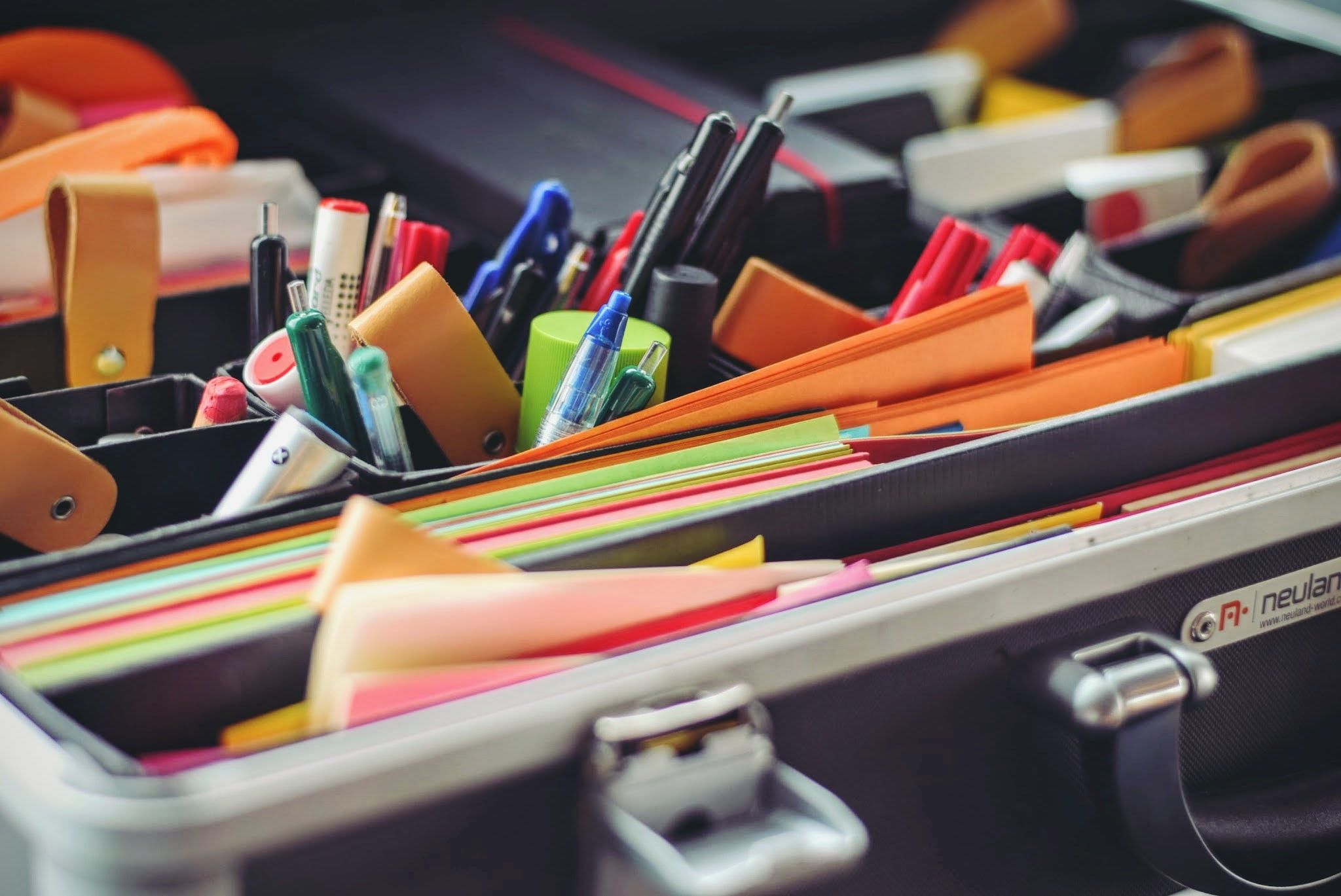 An open case packed with pens, highlighters and stacks of colourful sticky notes